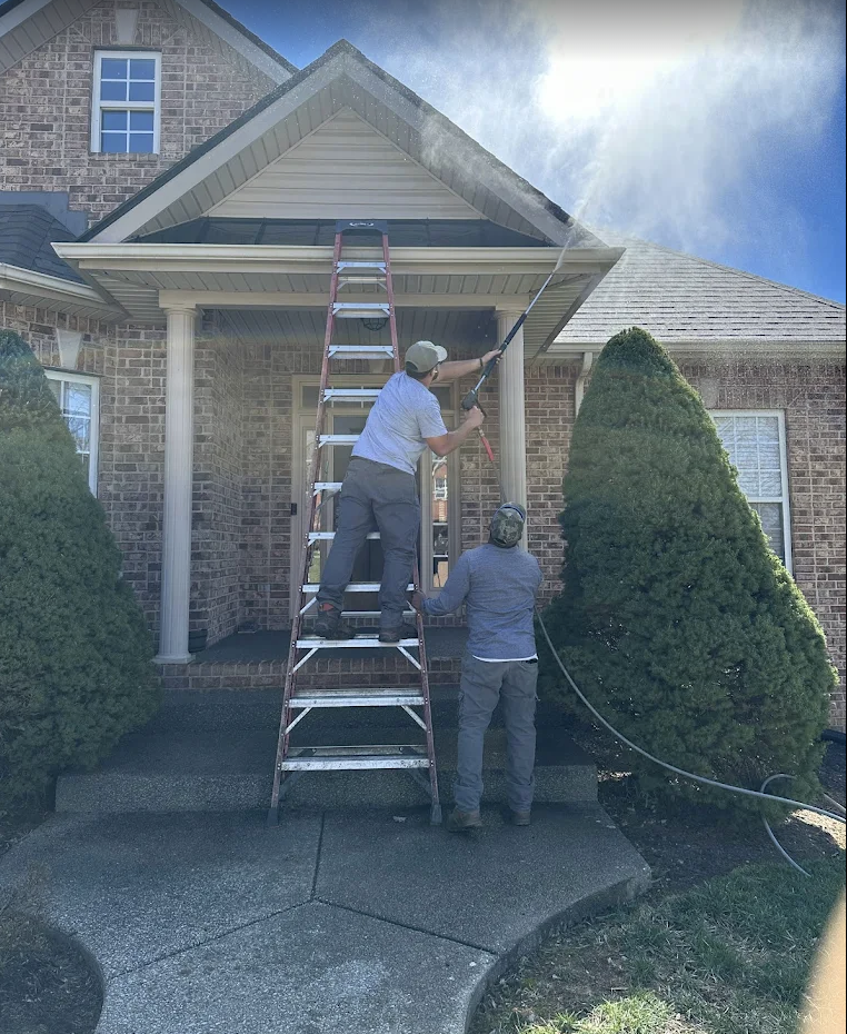 Gonzalez Landscaping team pressure washing the exterior of a front porch and roofline.